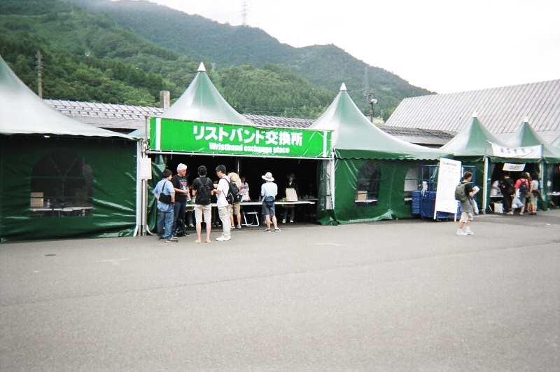 フジロックフェスティバルの会場に到着するとまずここへ行ってチケットとリストバンドを交換します。キャンプ・サイトのリストバンドもここで交換します。キャンプサイトを利用する人はリストバンドを2つつけることになります。リストバンドがないとキャンプサイトすら入れません。したがってテント設営もできないのでその場で装着してしまいましょう。