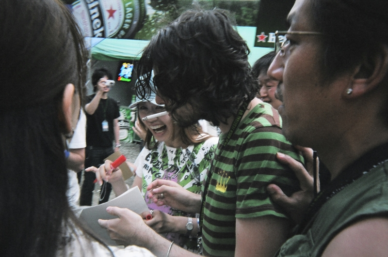 オアシスでサインを求められるくわえタバコのアーティスト。出演者用のパスを首から提げています。誰なのか分かりません。