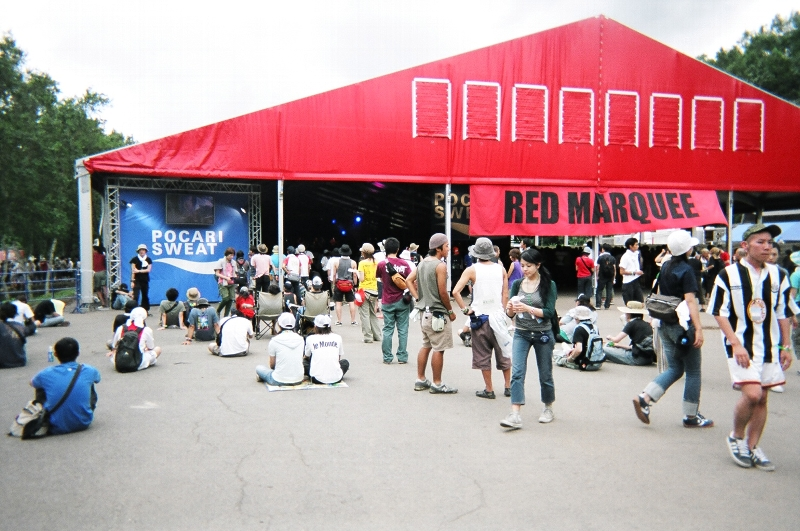 レッド・マーキーの後方。左右にテレビがついており、ライブをそのまま流しています。人気アーティストの場合、このあたりも人で埋まります。前夜祭のライブもレッド・マーキーで行われます。