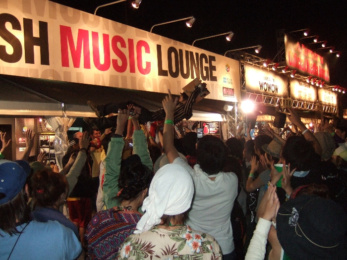 3日目終演後、オアシス・エリアでオアシスの「オアシス」のレコード・ジャケットをかぶった人が胴上げされています。