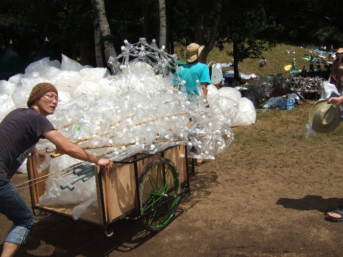 ホワイト・ステージ後方で作っていたペットボトルのオブジェとごみ袋を運ぶ人。