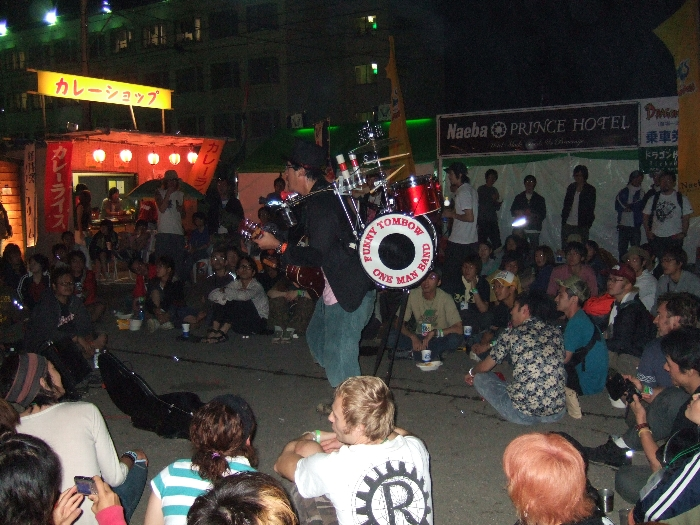 場外ショップエリアでワンマンバンドをする大道芸人。