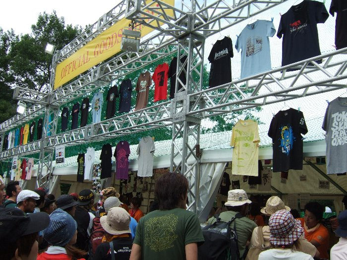 売り場の上に飾られているTシャツは一部です。アーティストによってはデザインが3、4種類、色違いもありますが、飾られるのはおおむね1アーティスト1デザインなので、実際に並んで最前列まで行かないと全商品は見られません。大量のアーティストが個別に商品を作っているので、事前にカタログを作るのも難しいと思われます。