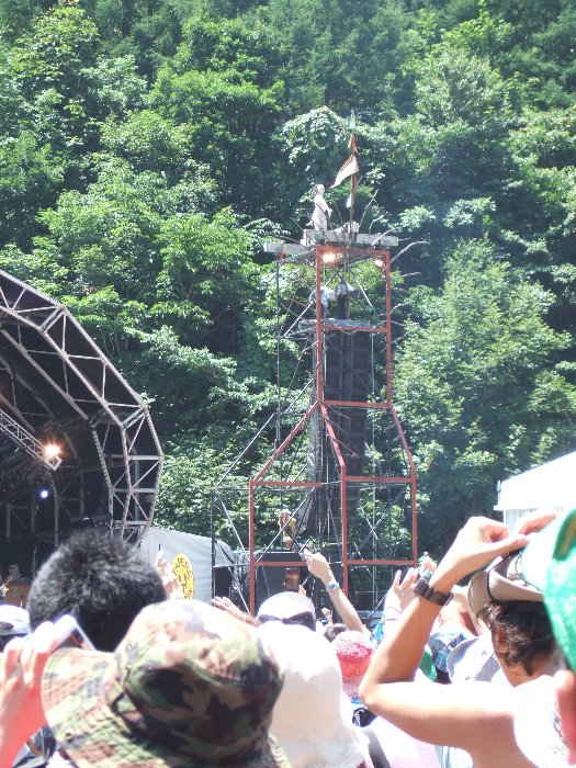 スピーカーと照明塔の上に登る渋さ知らズオーケストラの人。 