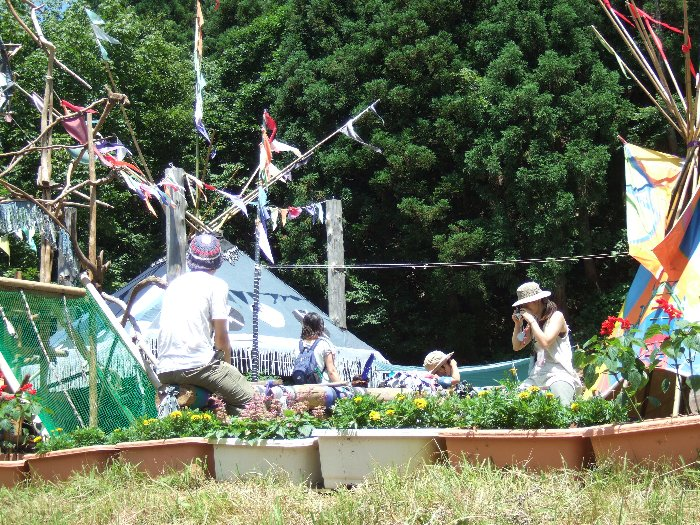 シーソーに乗りながら子どもの写真を撮るお母さん（多分）。