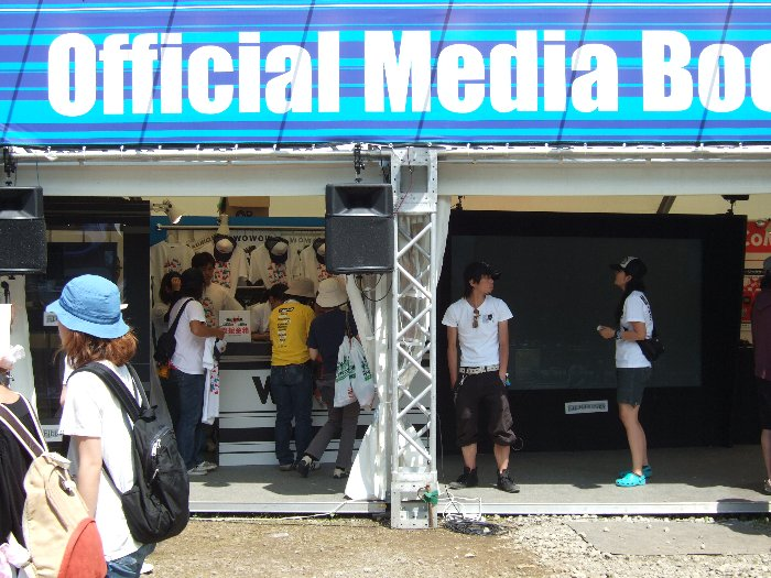 大画面の左にWOWOWのフジ・ロック限定Tシャツがあり、アーティストがサインを入れています。