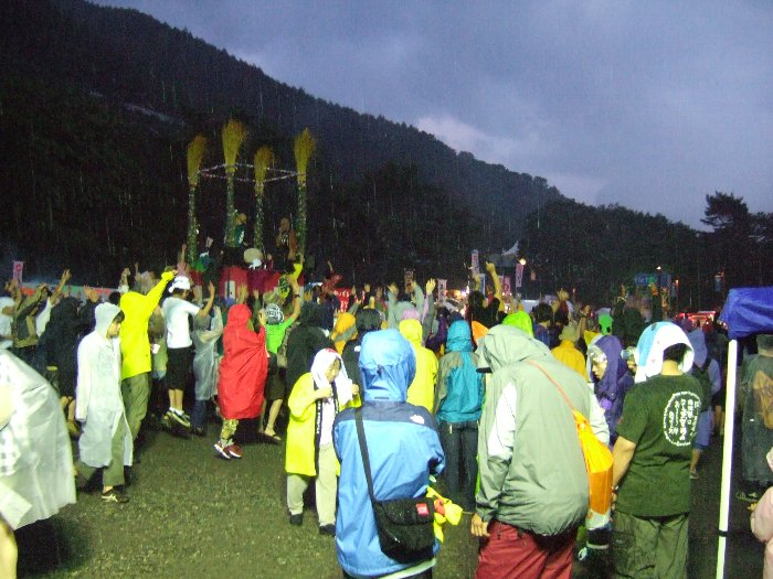 雨の中、苗場音頭で両手を挙げる人たち。苗場音頭、抽選会、花火、早食い競争、レッドマーキー前夜祭公演の流れは毎年変わりません。進行役の人も変わっていません。