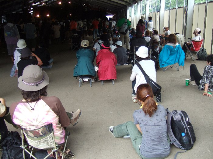 後方でいすに座って見る人たち。