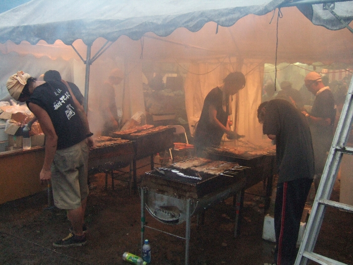 もうもうとした煙の中で串焼きを焼いています。 