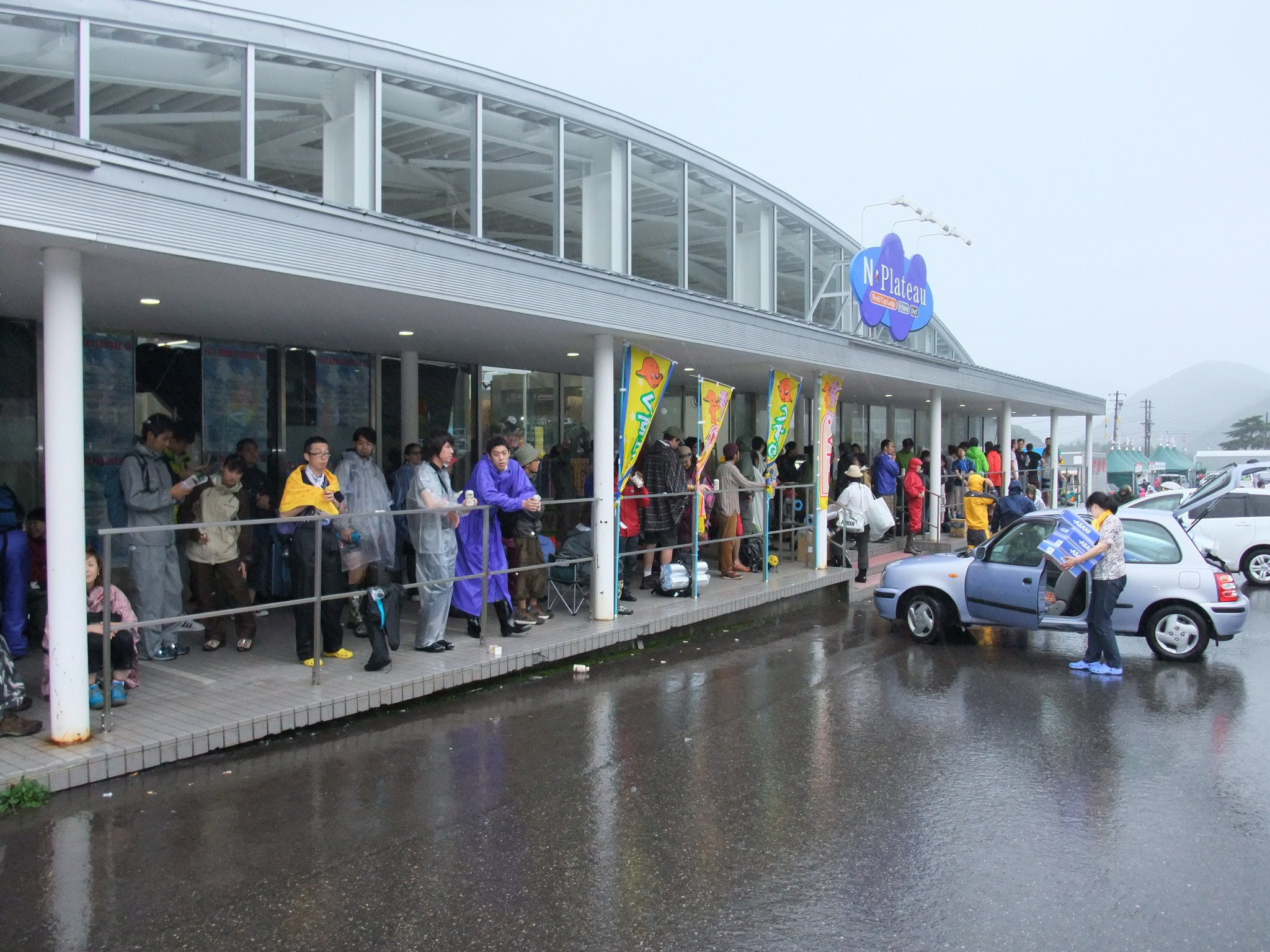 コンビニエンスストアで雨宿りする人たち。