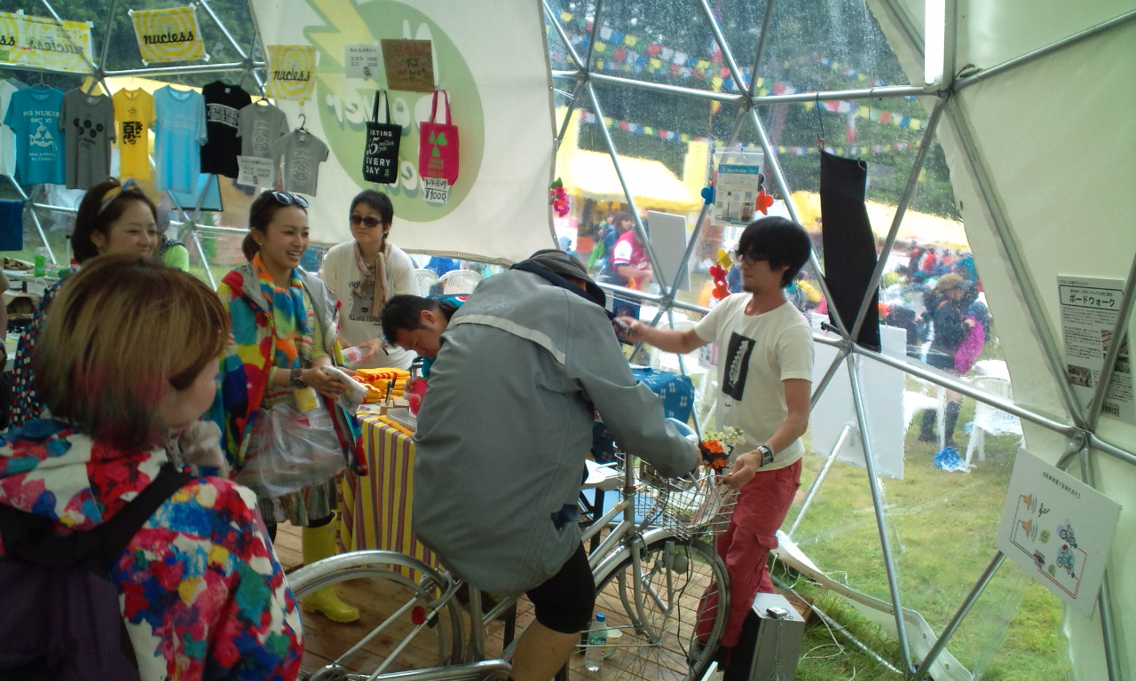 自転車をこいで発電する人と、応援する女性。