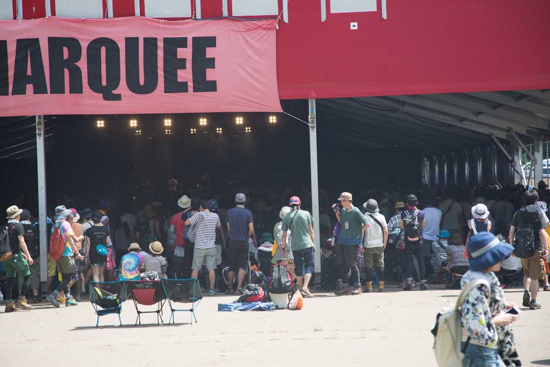 強い日差しを避けるかのように、日陰に人が詰まっている。