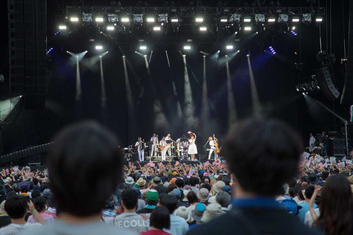 旭日旗に似た旗を振る椎名林檎。サザンオールスターズの件と同様に、ライブでの演出によって時代の空気を反映させている。ポピュラー音楽の聴衆は大多数が大衆であるため、アーティストが意識しようがしまいが音やファッションやライブにその時期の社会の嗜好が現れる。椎名林檎が旗を振り、観客に振らせるのは、椎名林檎が社会の空気を読み取っていて、物議を醸すことを織り込み済みでその空気を具体化しようとしたからと言える。旗のデザインをわざわざ旭日旗に似せているのはその空気に意識的であるからこそであり、旗をステージ上で振ってみせるのは挑発的メッセージだ。椎名林檎は、ステージ上でMCによって反戦を訴えても大して響かないことを知っているし、自分のライブの雰囲気に合わないことが分かっているからこうした演出になる。サザンオールスターズは親しみやすい雰囲気を持っているがゆえに反響が大きくなり、件の後にラジオで弁明をしているが、椎名林檎は一切しないだろうし、する必要もないだろう。