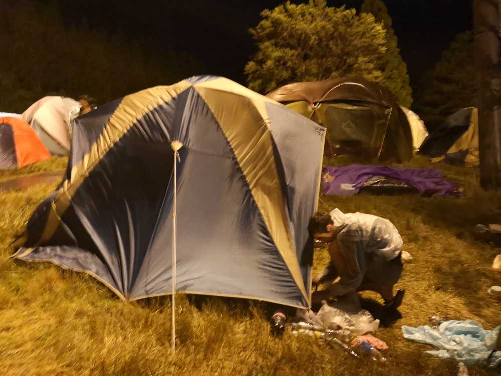 深夜にテントを立て直す白人男性。日曜午前1時20分ごろ。