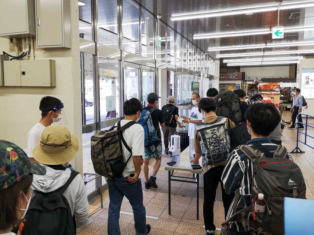 体温チェックと同時に消毒液が出る機械に手を当てます。このあと、体温チェック済みのリストバンドを配布。