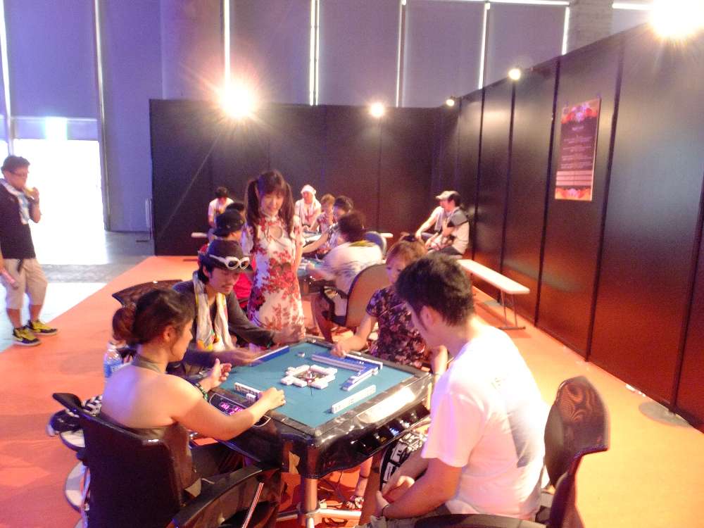 チャイナドレスの女性が参加するマージャン卓。