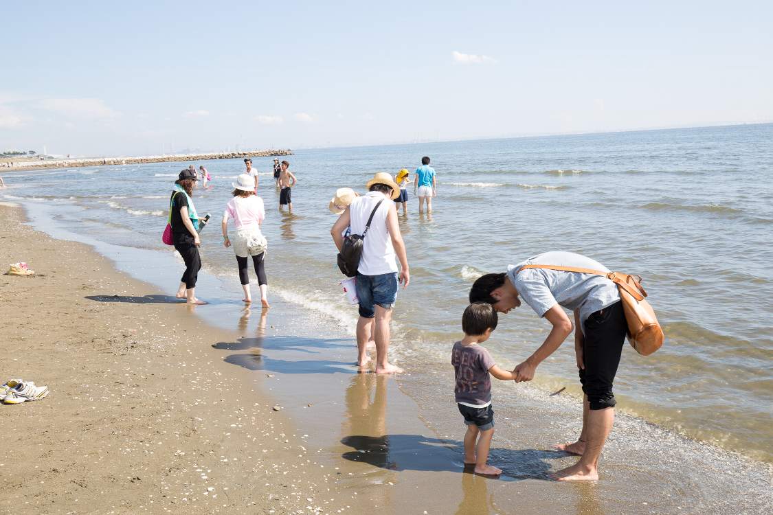 裸足になって海に入る人。