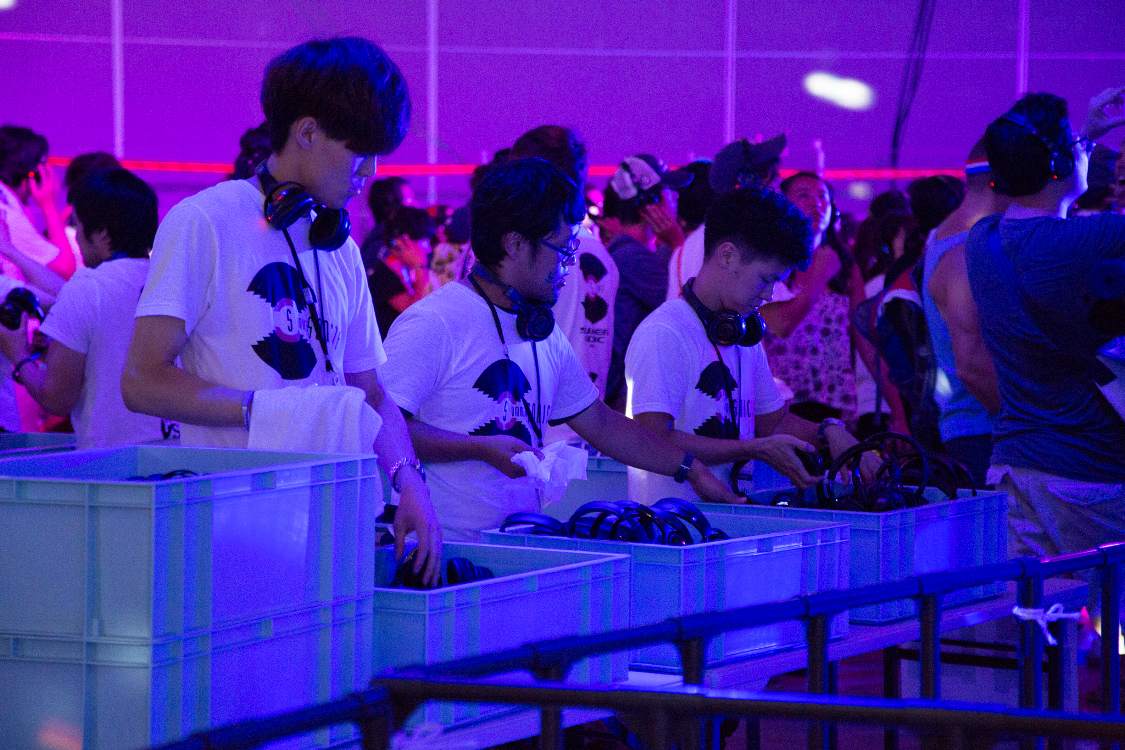 返却されたヘッドホンを掃除する人。