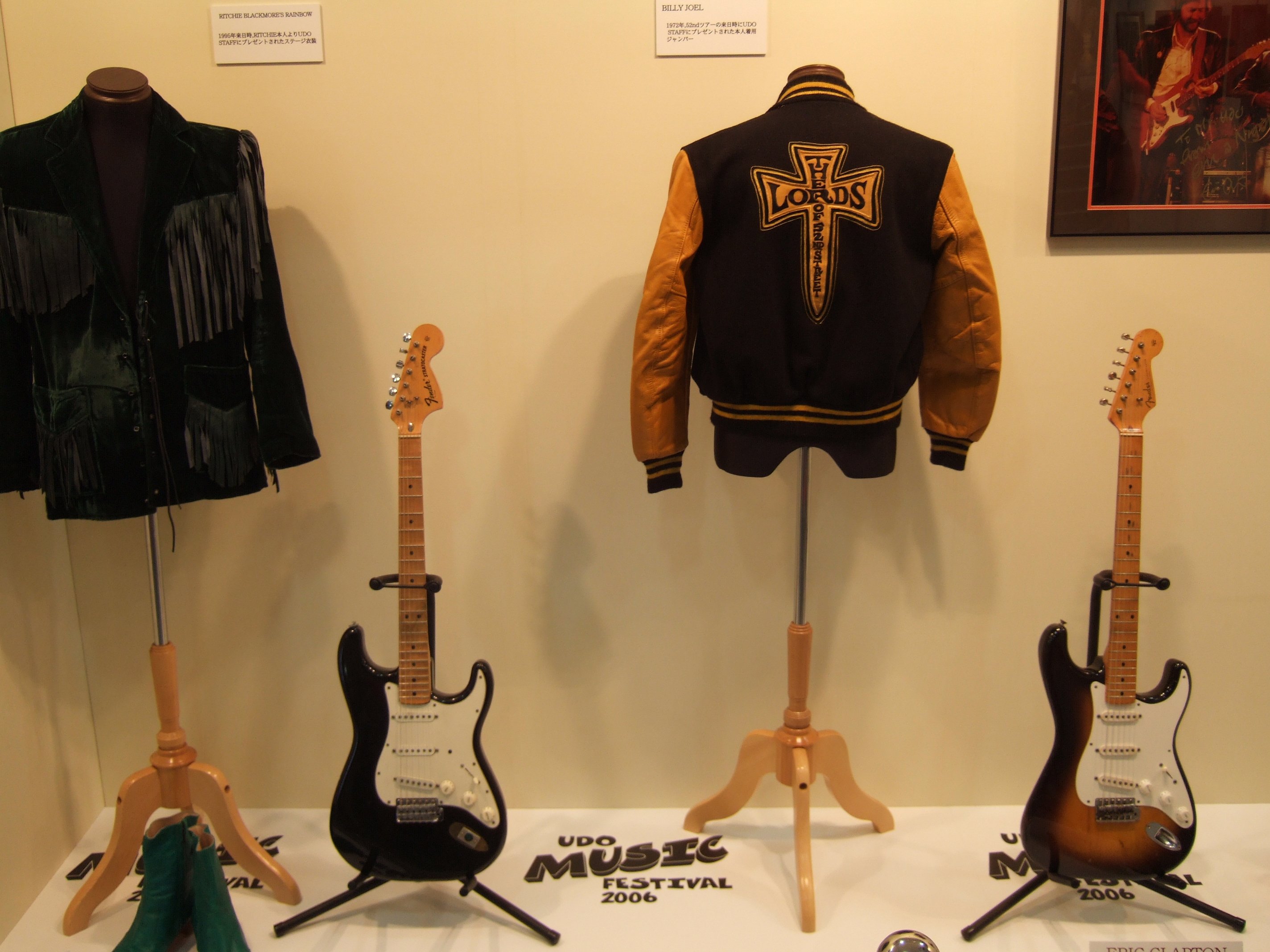 左の衣装はブラックモアズ・レインボーのリッチー・ブラックモアが1995年の「孤高のストレンジャー」のライブで来日した際着ていた服。右はビリー・ジョエルが1972年の「ニューヨーク52番街」の来日公演で着ていた服。右のギターはエリック・クラプトン。